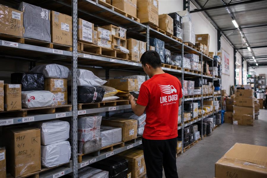 Сотрудник LINE CARGO у стеллажей с посылками